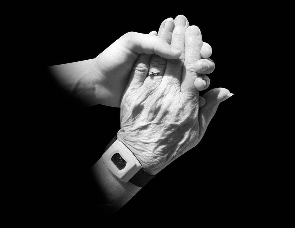 a young hand holding an old hand giving support